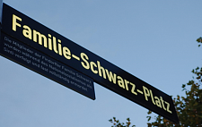 Das Bild zeigt das Straßenschild des Familie-Schwarz-Platzes im Abendlicht