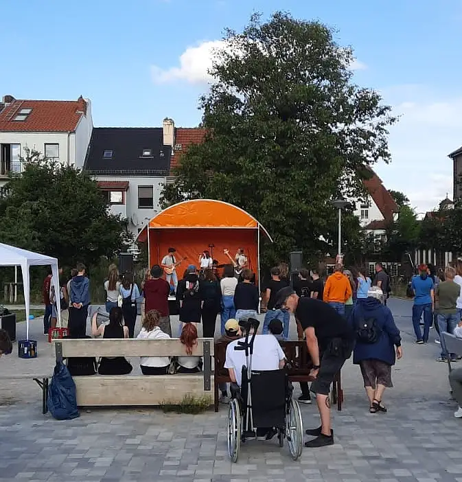 Das Bild zeigt die Bühne mit Musiker:innen und Publikum im Vordergrund